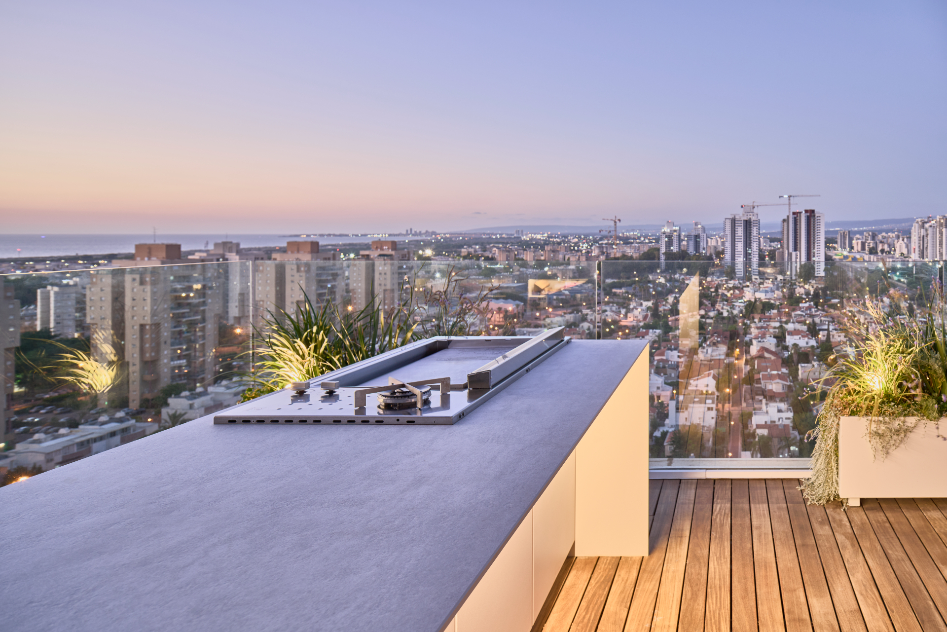 Capo Cuòco rooftop outdoor kitchen at dusk with city skyline